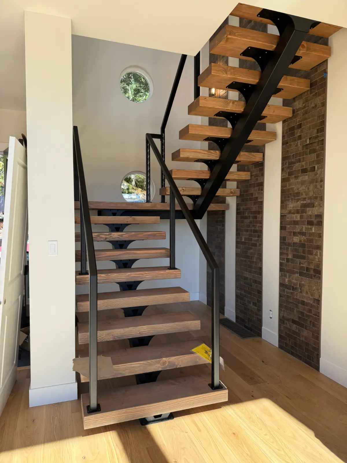 Floating mono-stringer stair rising beside a stone feature wall